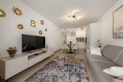 a living room with a couch and a tv and a table at Beautiful apartment Cannes center terrace parking in Cannes
