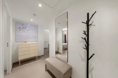 a white bedroom with a mirror and a chair at Beautiful apartment Cannes center terrace parking in Cannes