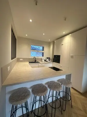 a kitchen with three bar stools in front of a counter at Spacieux et Moderne T2 près du centre in Cannes