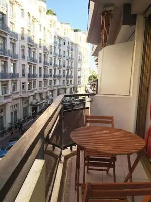 a balcony with a wooden table and chairs on a building at Cannes 2pièces Croisette Martinez in Cannes