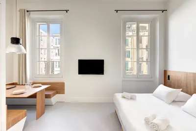 a white bedroom with a bed and a desk and windows at Immogroom - 2 min du palais - Studio - Luxury - AC in Cannes