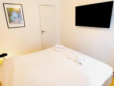 a bedroom with a white bed with a flat screen tv at Design Appartment 100sqm close to Palais Beach and Restaurants in Cannes