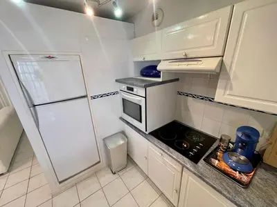 a small kitchen with white cabinets and a refrigerator at Le Palazzio by Connexion in Cannes
