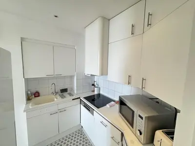 a white kitchen with a sink and a microwave at charmante suite vue mer villa Carmela in Cannes