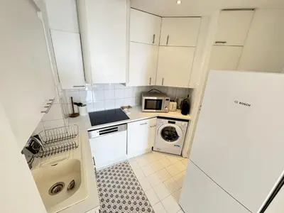 a small kitchen with white cabinets and a washing machine at charmante suite vue mer villa Carmela in Cannes