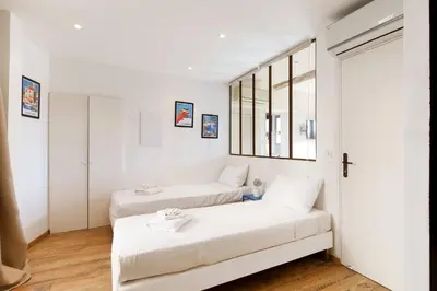 two beds in a room with white walls and a window at CASA RIVIERA Ecrin moderne ,tout confort, 300 m Croisette in Cannes