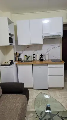 a kitchen with white cabinets and a glass table at Studio in Cannes