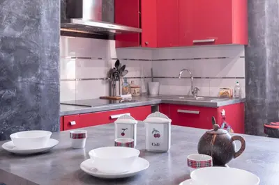 a kitchen with red cabinets and white dishes on a counter at The Artists’ Retreat – Comfort in the Heart of Cannes in Cannes