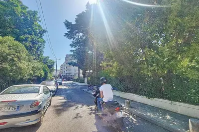 a man riding a motorcycle down a street with a car at Henri Camille Real Estate- Mikaela - Studio with terrace in Cannes