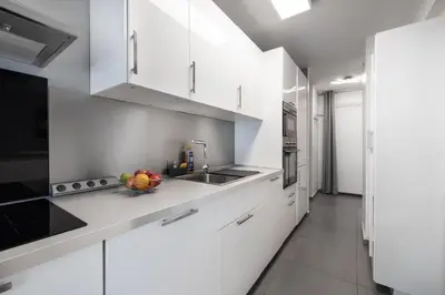 a white kitchen with a bowl of fruit on the counter at Suite Ioana - Appartement à Cannes in Cannes