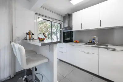 a white kitchen with white cabinets and a sink at Suite Ioana - Appartement à Cannes in Cannes