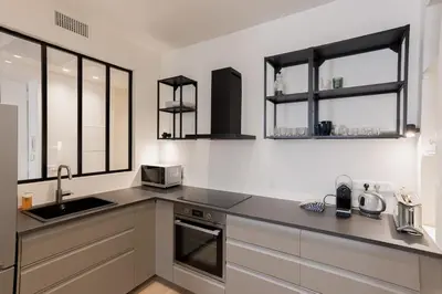 a kitchen with white cabinets and a sink and windows at 14 Vagliano - Palais, plage, clim, hyper-centre in Cannes