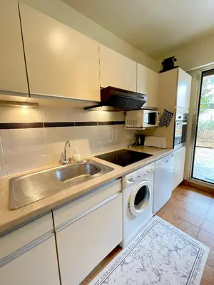 a kitchen with a sink and a washing machine at appartement avec piscine in Le Cannet