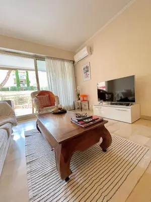 a living room with a coffee table and a flat screen tv at appartement avec piscine in Le Cannet