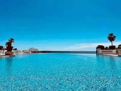 a large pool with blue water and palm trees at 4 people with Pool Tennis Parking air cond in Cannes