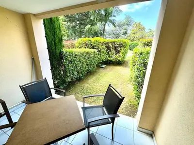 a balcony with a table and chairs and a garden at 4 people with Pool Tennis Parking air cond in Cannes