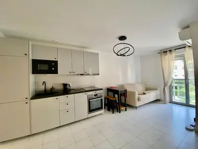a kitchen with white cabinets and a living room at Modern Apartment in Cannes in Cannes