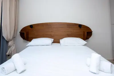 a bed with a wooden headboard and white sheets at Studio Merlot - Welkeys in Cannes