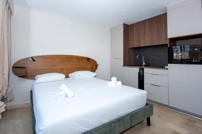 a bedroom with a white bed with a wooden headboard at Studio Merlot - Welkeys in Cannes