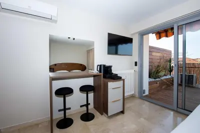 a kitchen with stools at a counter and a balcony at Studio Merlot - Welkeys in Cannes