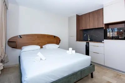 a bedroom with a large white bed with a wooden headboard at Studio Merlot - Welkeys in Cannes