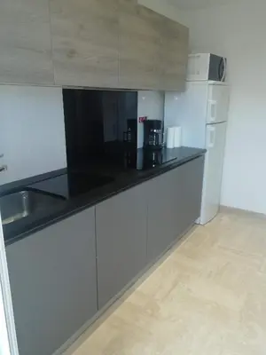 a kitchen with white cabinets and a black counter top at Appartement cannes in Le Cannet