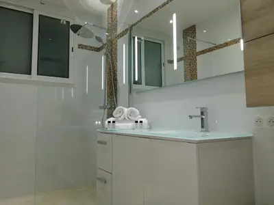 a white bathroom with a sink and a mirror at Appartement cannes in Le Cannet