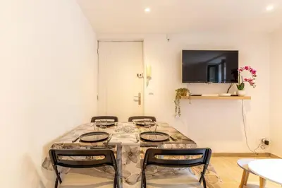 a room with a table with chairs and a tv at La Suquétane - Appt proche plage Cannes in Cannes