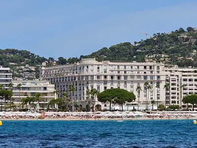 a large building on a beach with chairs and umbrellas at Cannes Croisette Miramar escape in Cannes