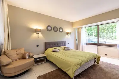 a bedroom with a bed and a chair and a window at Villa Emilia, vue mer, Super-Cannes in Vallauris