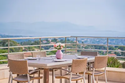 a table with chairs and a vase of flowers on a balcony at Villa Emilia, vue mer, Super-Cannes in Vallauris