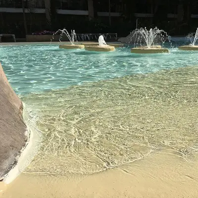 a pool of water with two fountains and a beach at Azuria in Cannes