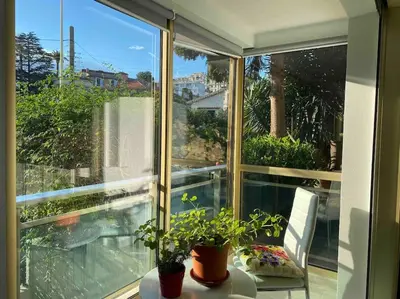 a screened in porch with a table and plants at Lovely Flat with Covered Balcony in Cannes in Cannes
