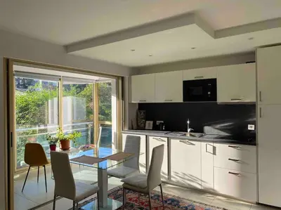 a kitchen with white cabinets and a table and chairs at Lovely Flat with Covered Balcony in Cannes in Cannes