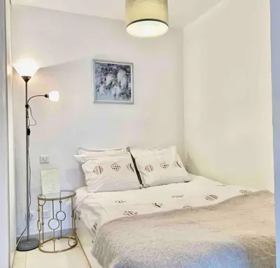 a white bedroom with a bed and a lamp at Lovely Flat with Covered Balcony in Cannes in Cannes