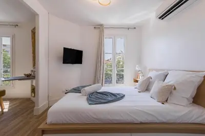 a bedroom with a large white bed with a window at Studio Jasmin - calme charmant clim Palais & plage in Cannes