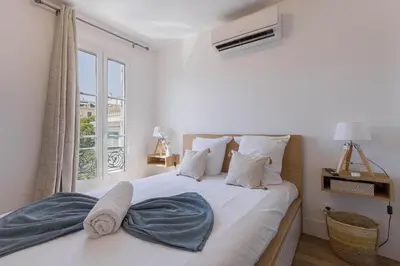 a bedroom with a large white bed with a window at Studio Jasmin - calme charmant clim Palais & plage in Cannes