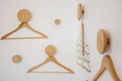 four wooden hangers on a white wall with a wooden object at Studio Jasmin - calme charmant clim Palais & plage in Cannes