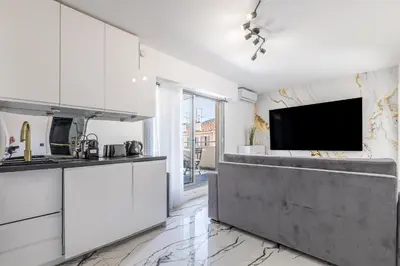 a kitchen with white cabinets and a flat screen tv at LB Vacation Rentals I A Quiet Place with Terrace in the Heart of Cannes in Cannes