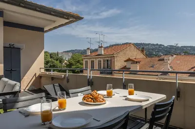 a table with a plate of food on a balcony at LB Vacation Rentals I A Quiet Place with Terrace in the Heart of Cannes in Cannes