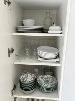 a white cabinet filled with plates and dishes at studio standing cannes croisette in Cannes