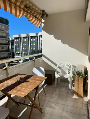 a balcony with a wooden table and white chairs at studio standing cannes croisette in Cannes
