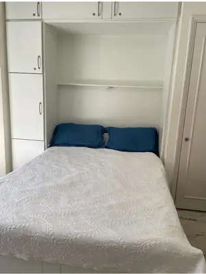 a bed with blue pillows in a small bedroom at studio standing cannes croisette in Cannes