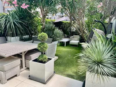 a patio with a table and chairs and plants at Jardin sur la Pointe Croisette Luxe en Bord de Mer in Cannes