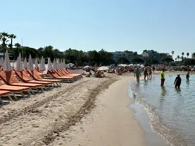 a beach with chairs and umbrellas and people in the water at Jardin sur la Pointe Croisette Luxe en Bord de Mer in Cannes