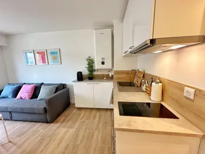 a living room with a couch and a kitchen at Studio cosy au cœur de Cannes in Cannes