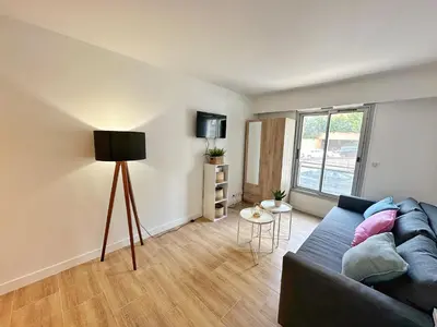 a living room with a blue couch and a window at Studio cosy au cœur de Cannes in Cannes