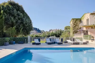 a swimming pool with lounge chairs next to a building at La Villa Julia Two in Vallauris