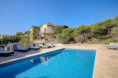 a swimming pool with chairs and a house at La Villa Julia Two in Vallauris