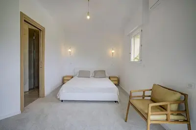 a white bedroom with a bed and a chair at La Villa Julia Two in Vallauris